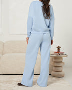 Komplet pudrowo niebieski z obniżoną linią ramion i szerokimi nogawkami - widok z tyłu
